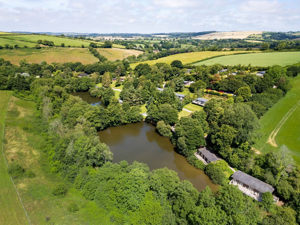 A view of a lake surrounded by trees and houses at 2 Tree Tops in Lanreath