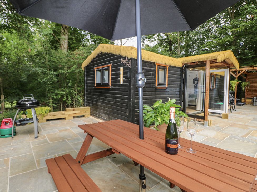 An outdoor area with a table, champagne, and cabins at Charltons Hollow Cabin in Haywards Heath
