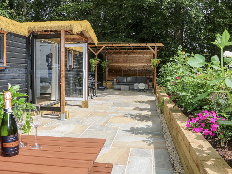 A garden with a cabin, outdoor seating, and plants at Charltons Hollow Cabin in Haywards Heath