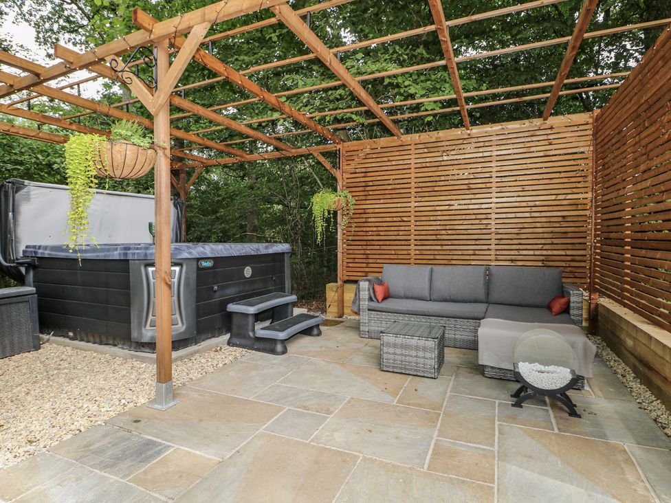 An outdoor area with a hot tub and a sofa at Charltons Hollow Cabin in Haywards Heath