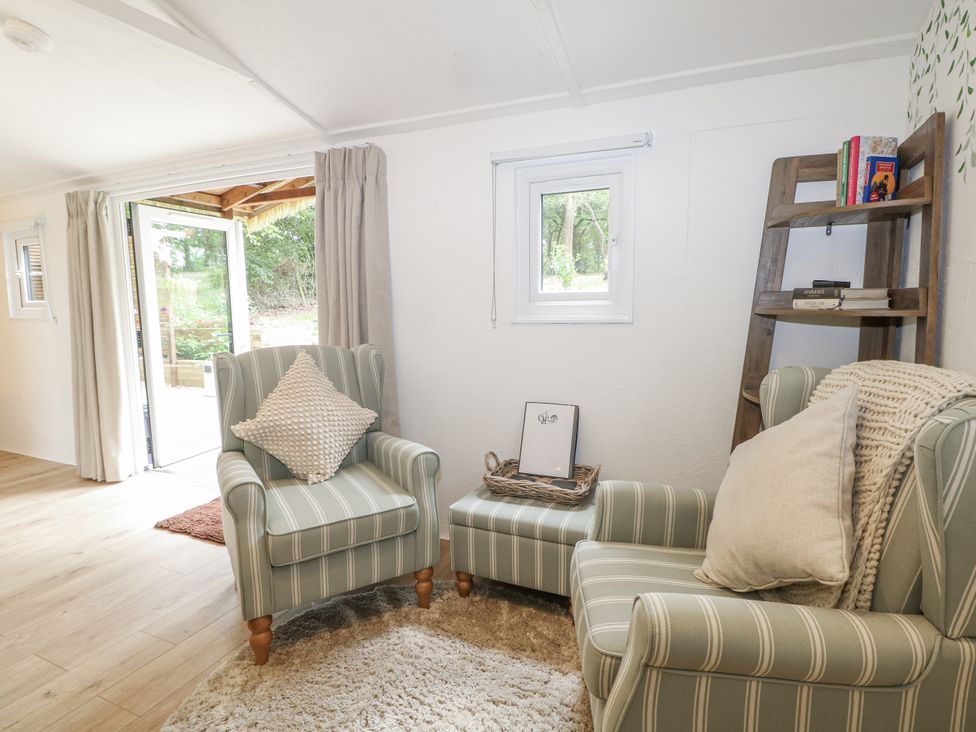 A snug with armchairs and a bookshelf at Charltons Hollow Cabin Haywards Heath