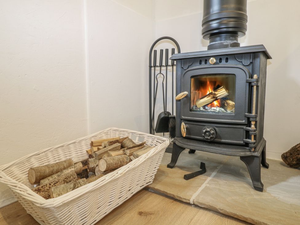 A living room with a wood stove and firewood at Charltons Hollow Cabin in Haywards Heath
