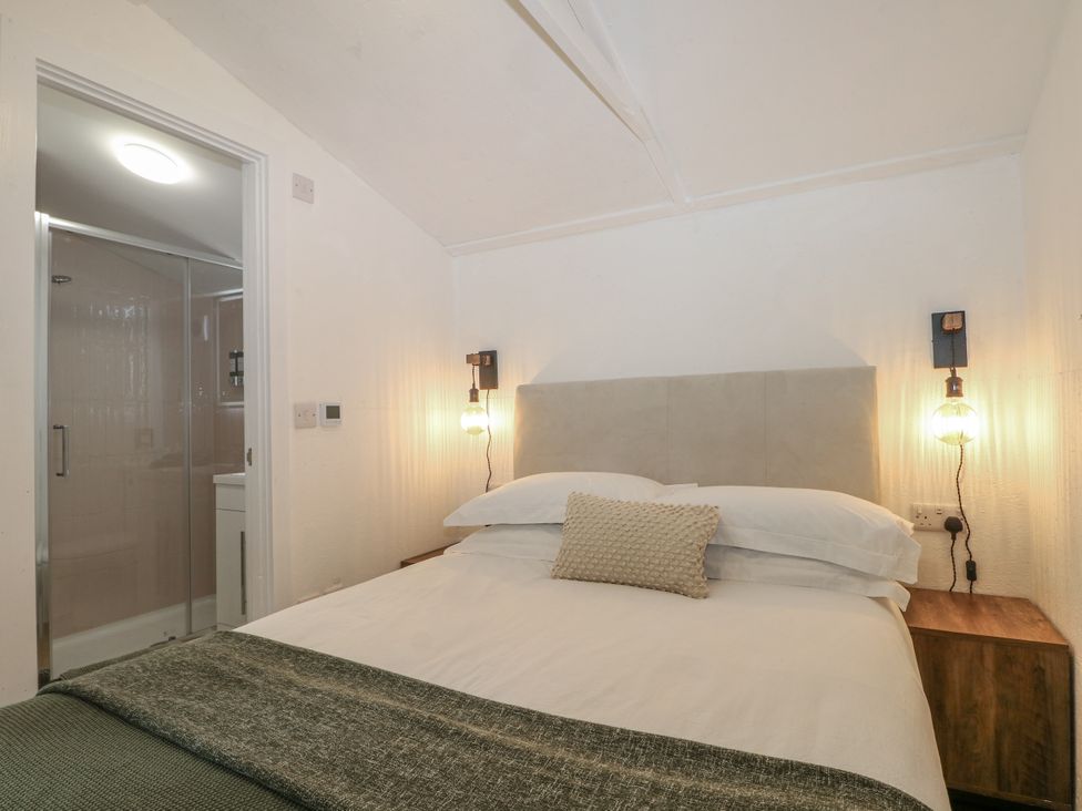 A bedroom with a bed and a bathroom door at Charltons Hollow Cabin Haywards Heath
