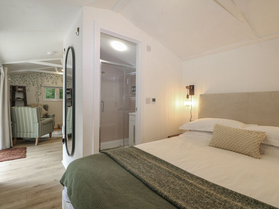 A bedroom featuring a bed and shower area at Charltons Hollow Cabin Haywards Heath
