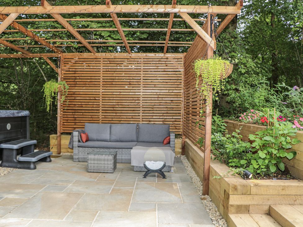 An outdoor seating area with a sofa and hot tub at Charltons Hollow Cabin in Haywards Heath