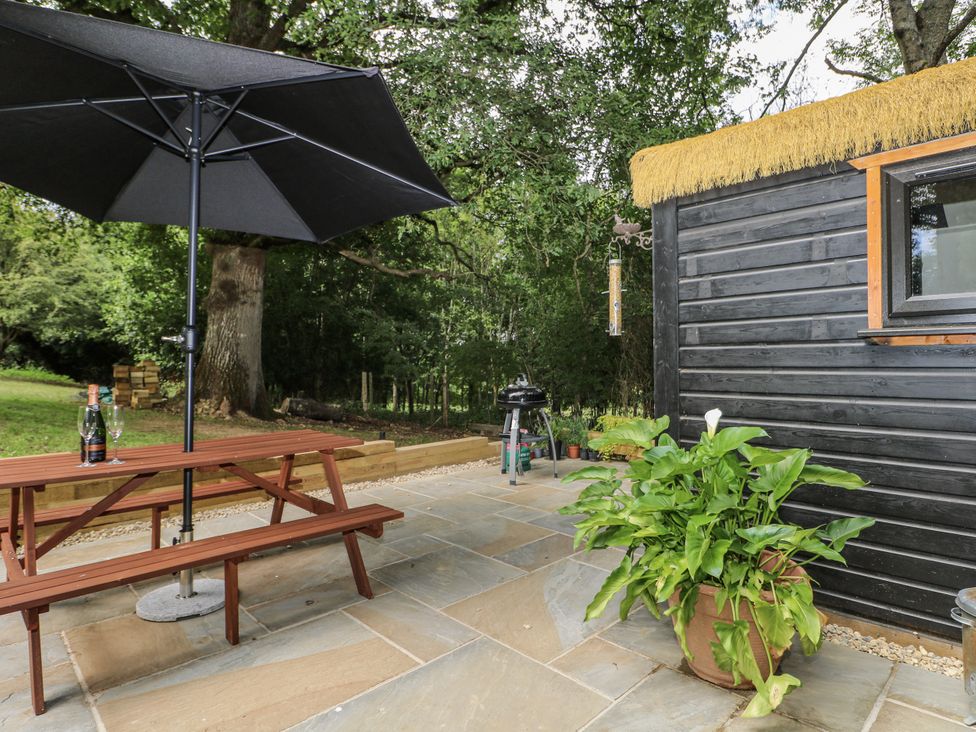 An outdoor seating area with a table and umbrella at Charltons Hollow Cabin in Haywards Heath
