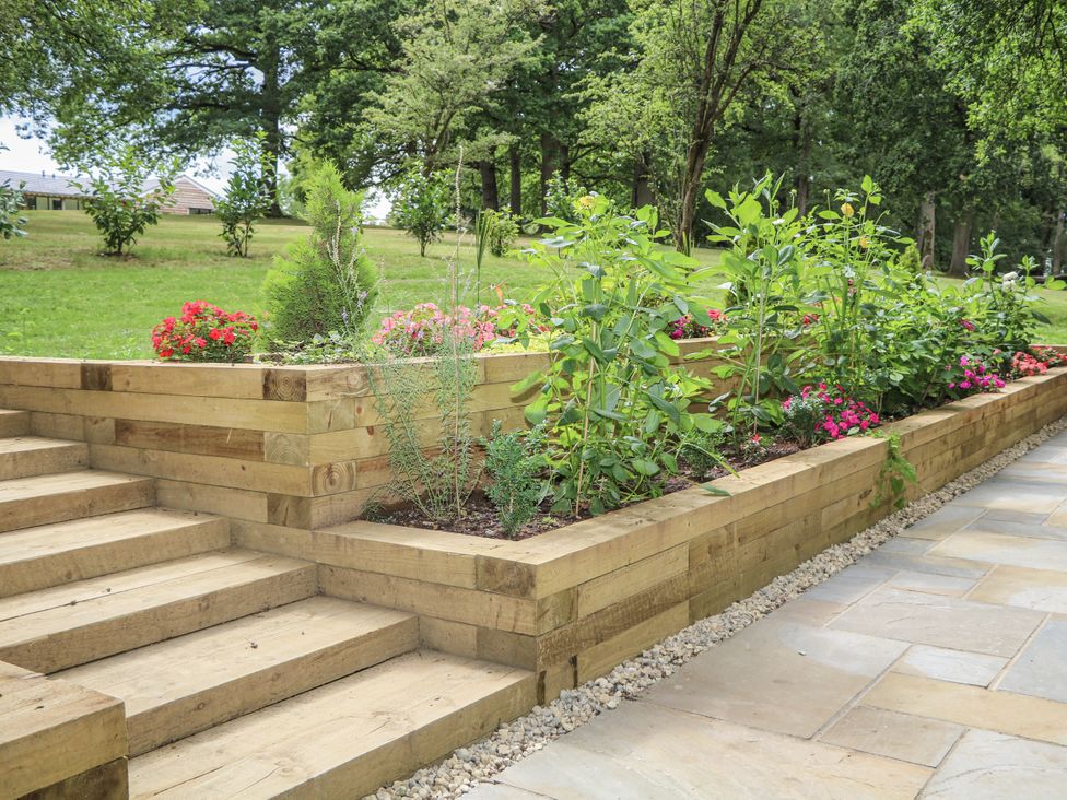 Garden with wooden steps and flower beds at Charltons Hollow Cabin in Haywards Heath