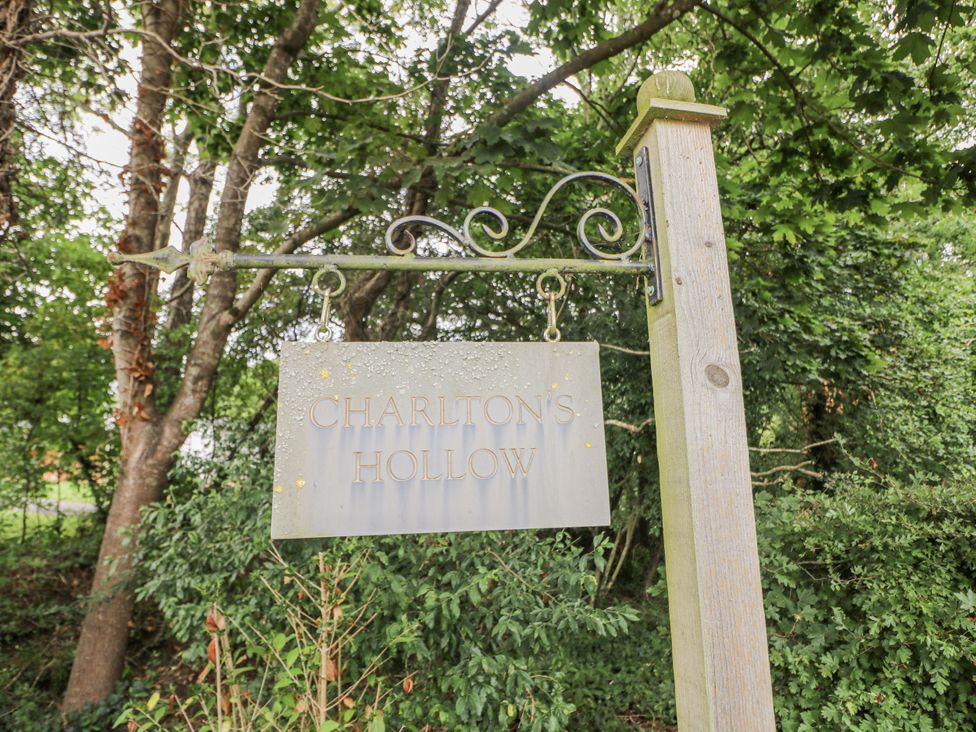 A sign for Charlton's Hollow surrounded by trees at Charltons Hollow Cabin Haywards Heath