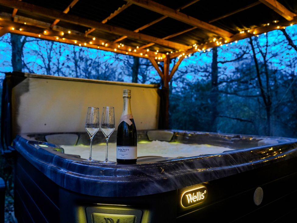 A hot tub with champagne and glasses at Charltons Hollow Cabin in Bolney