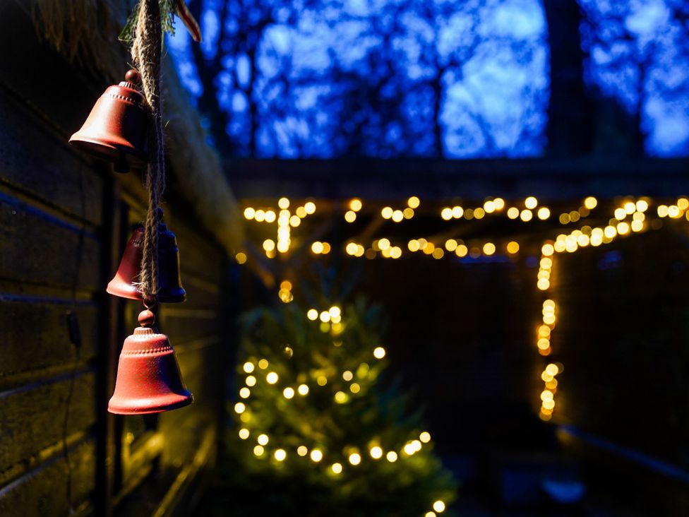 An outdoor area with bells, string lights, and a Christmas tree at Charltons Hollow Cabin Bolney