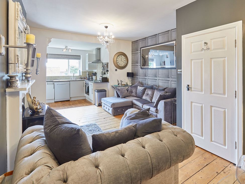 A living room with a sofa and kitchen area at Apartment 2 in Whitby