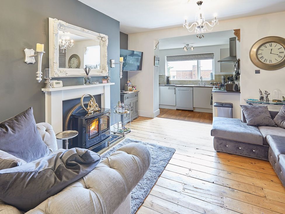 A living room with a fireplace and open kitchen at Apartment 2 in Whitby