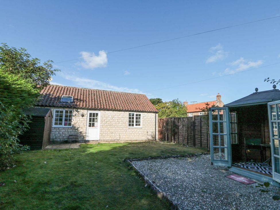 A garden with a cottage, shed and gravel area at Midsummer Cottage in Malton