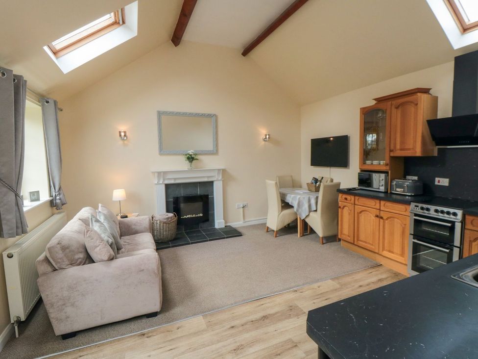 A living room with a fireplace and kitchen area at Midsummer Cottage in Malton