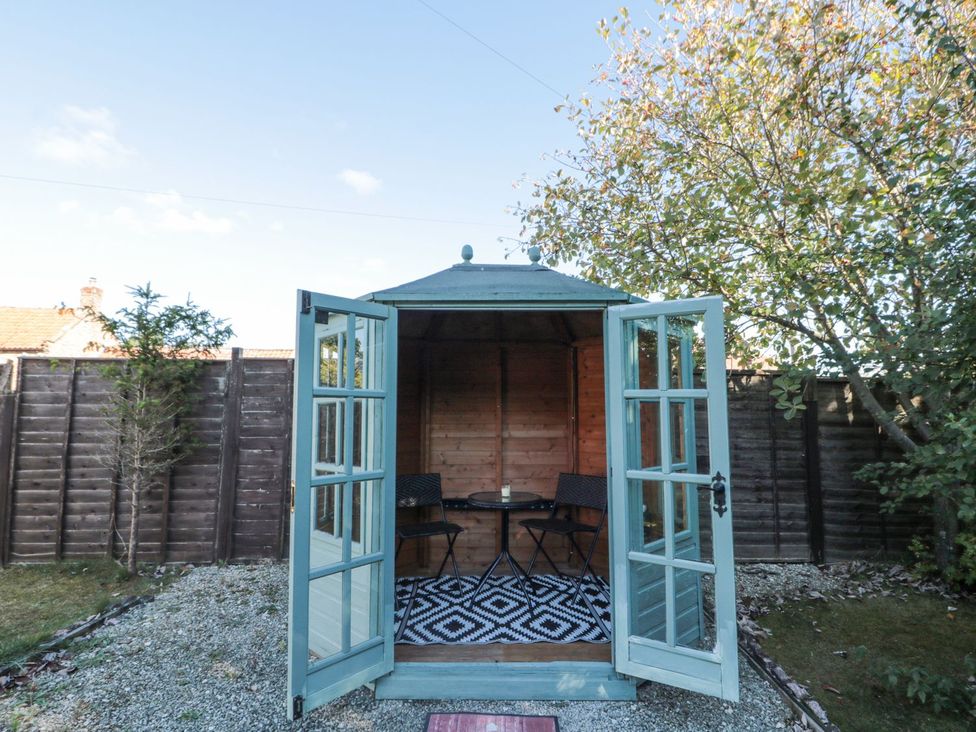 A garden with a gazebo containing a table and chairs at Midsummer Cottage in Malton