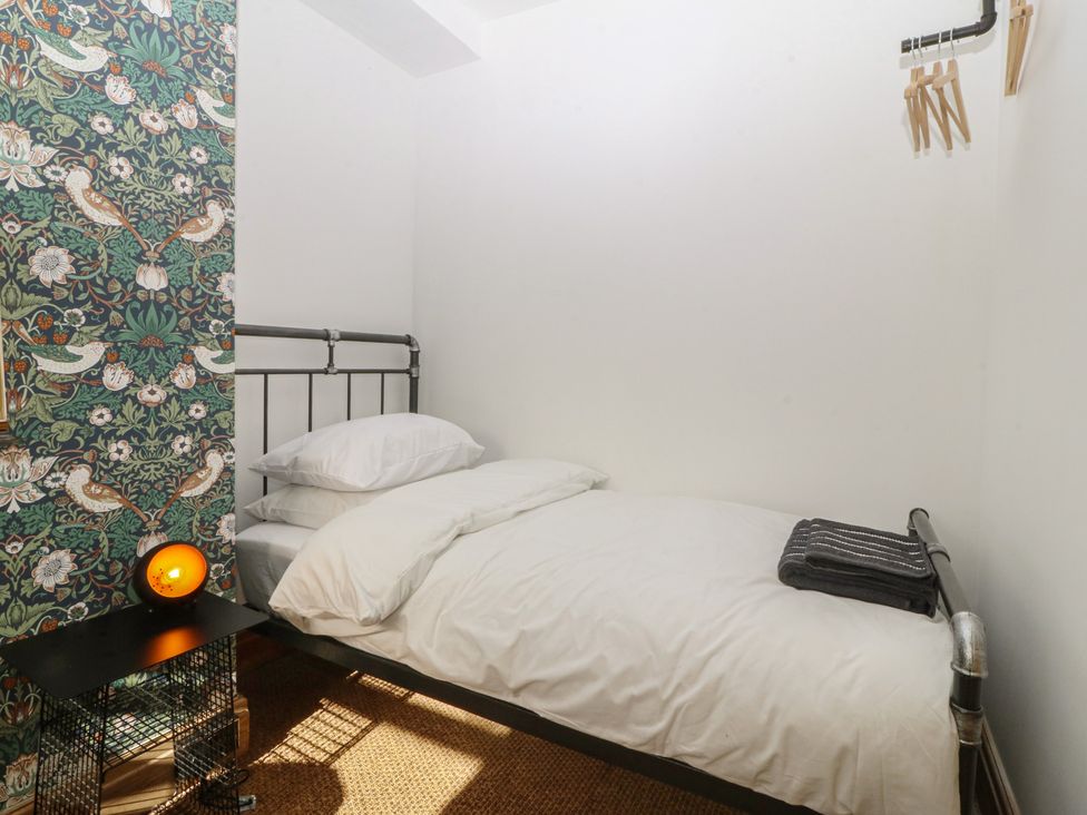 A bedroom with a bed and patterned wall at Ty Gelert in Conwy