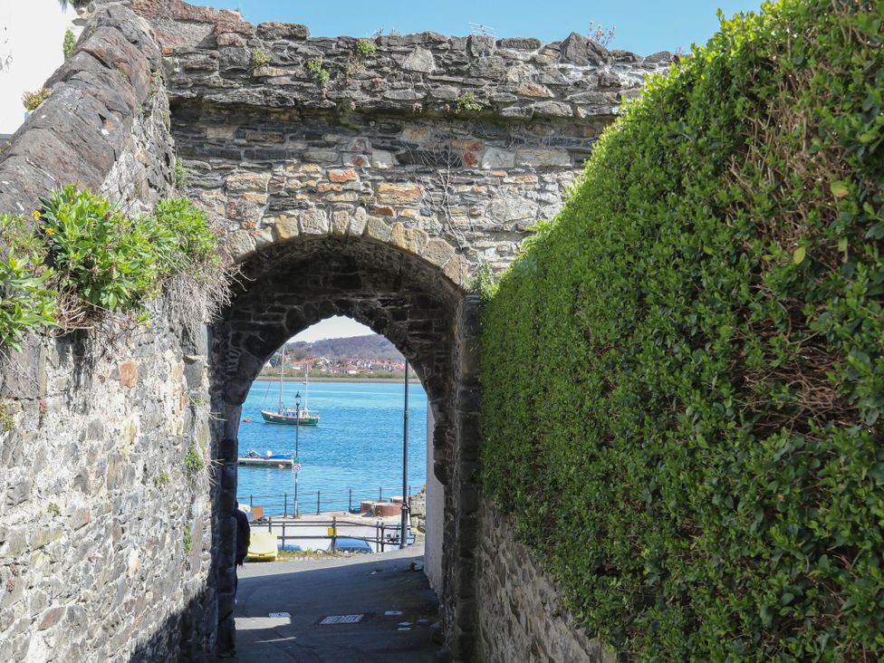 An archway with stone walls and a view of water and boats at Ty Gelert in Conwy