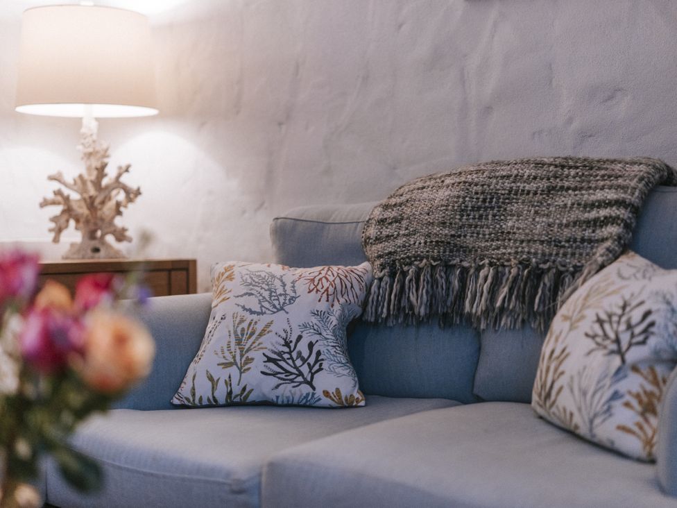 A living room featuring a sofa with pillows and a lamp at Tamarisk Cottage in St. Agnes