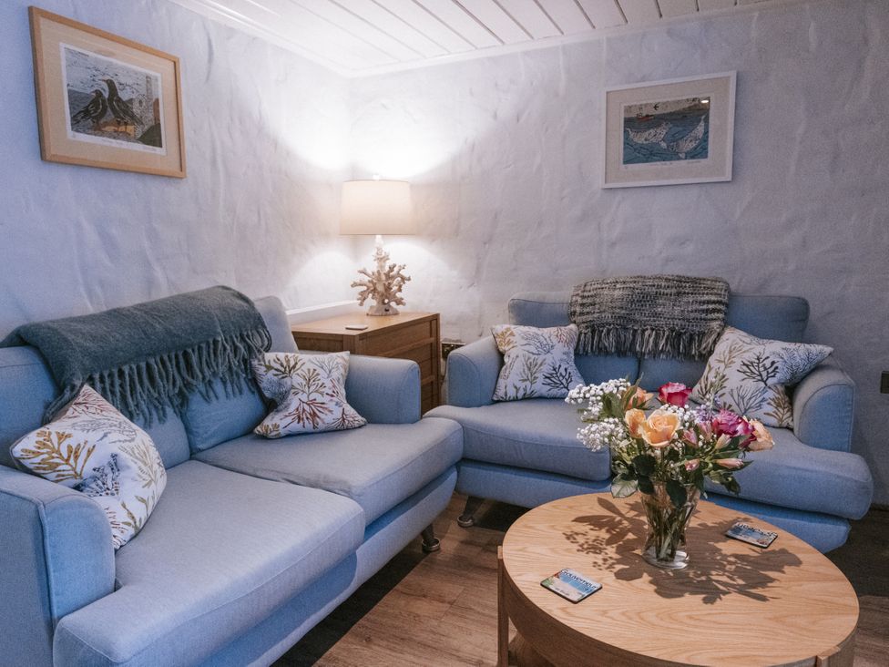 A living room with sofas and a flower vase at Tamarisk Cottage in St. Agnes