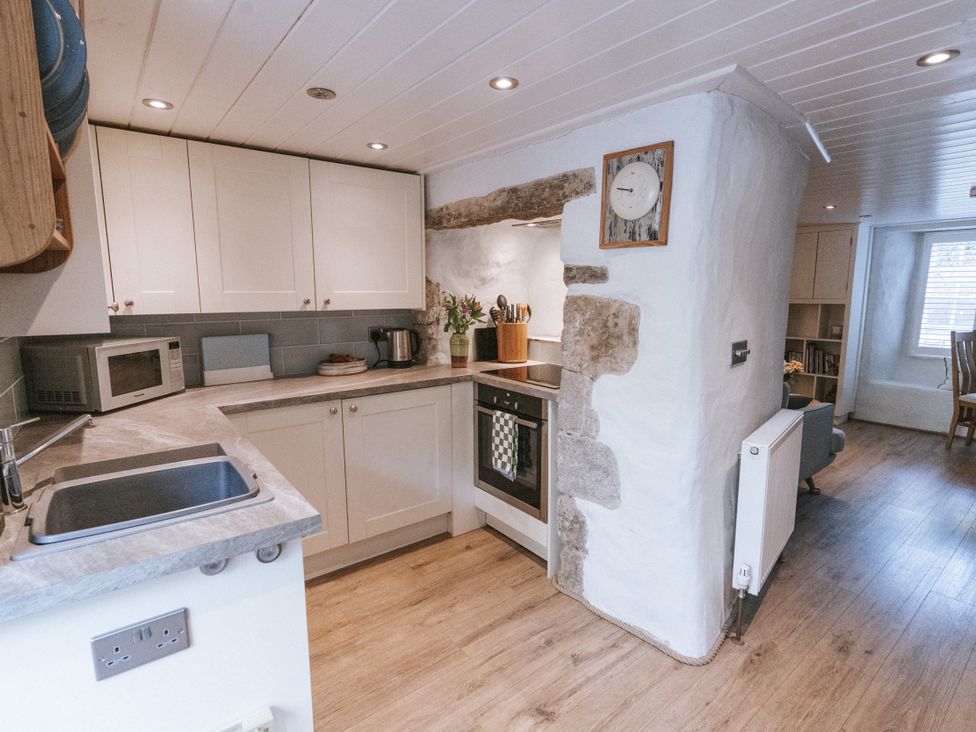 A kitchen with cabinets and appliances at Tamarisk Cottage in St. Agnes