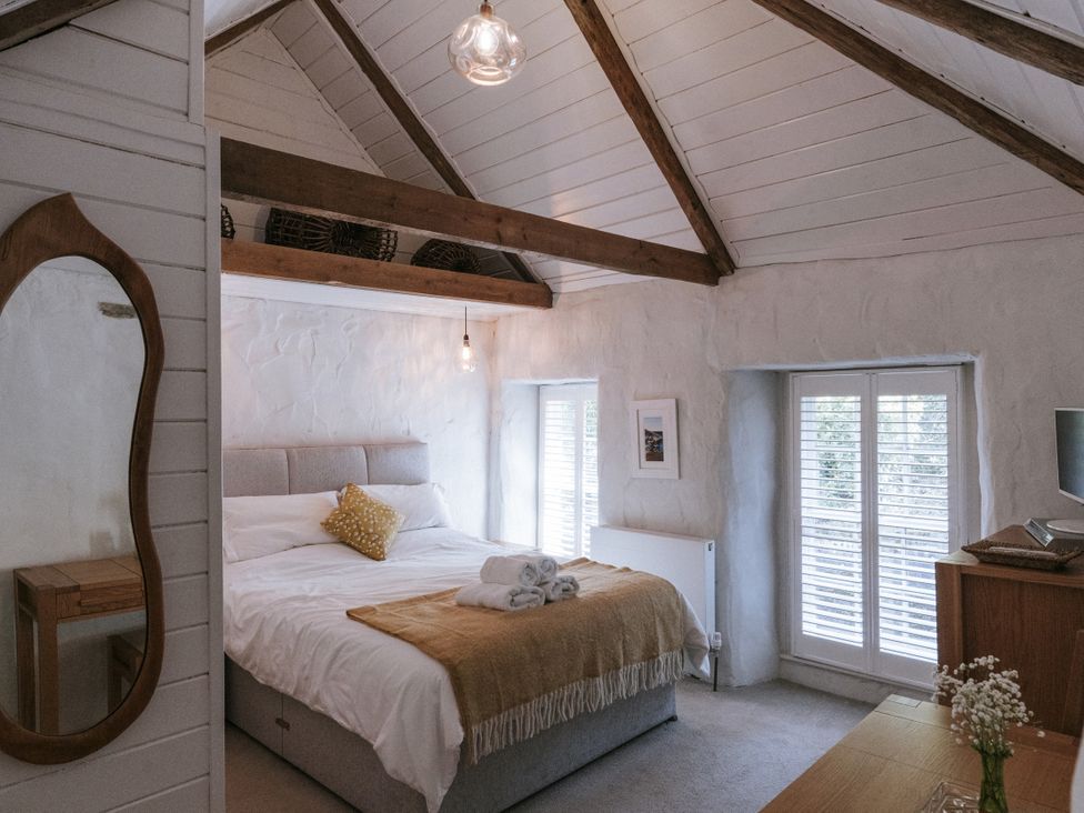 A bedroom with a bed and mirror at Tamarisk Cottage St. Agnes