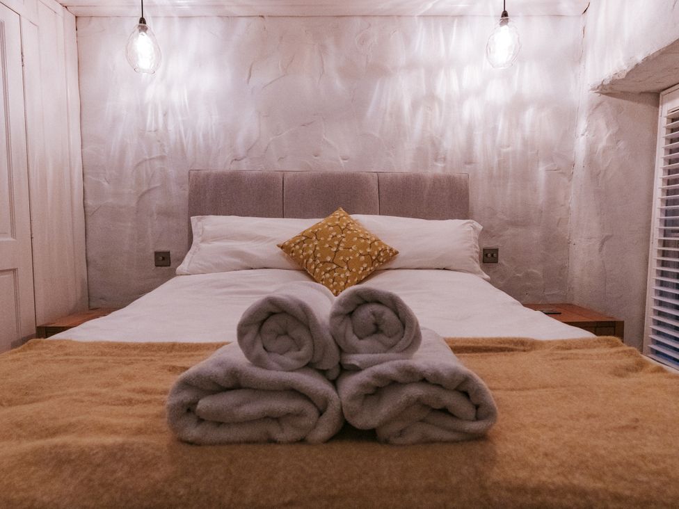 A bedroom with bed and towels at Tamarisk Cottage in St. Agnes