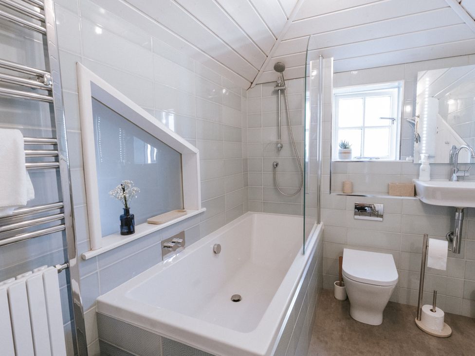A bathroom with a bathtub, shower, toilet, and sink at Tamarisk Cottage in St. Agnes