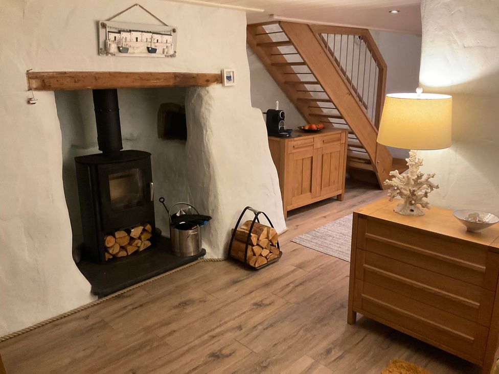 A living room featuring a wood stove and wooden cabinet at Tamarisk Cottage St Agnes