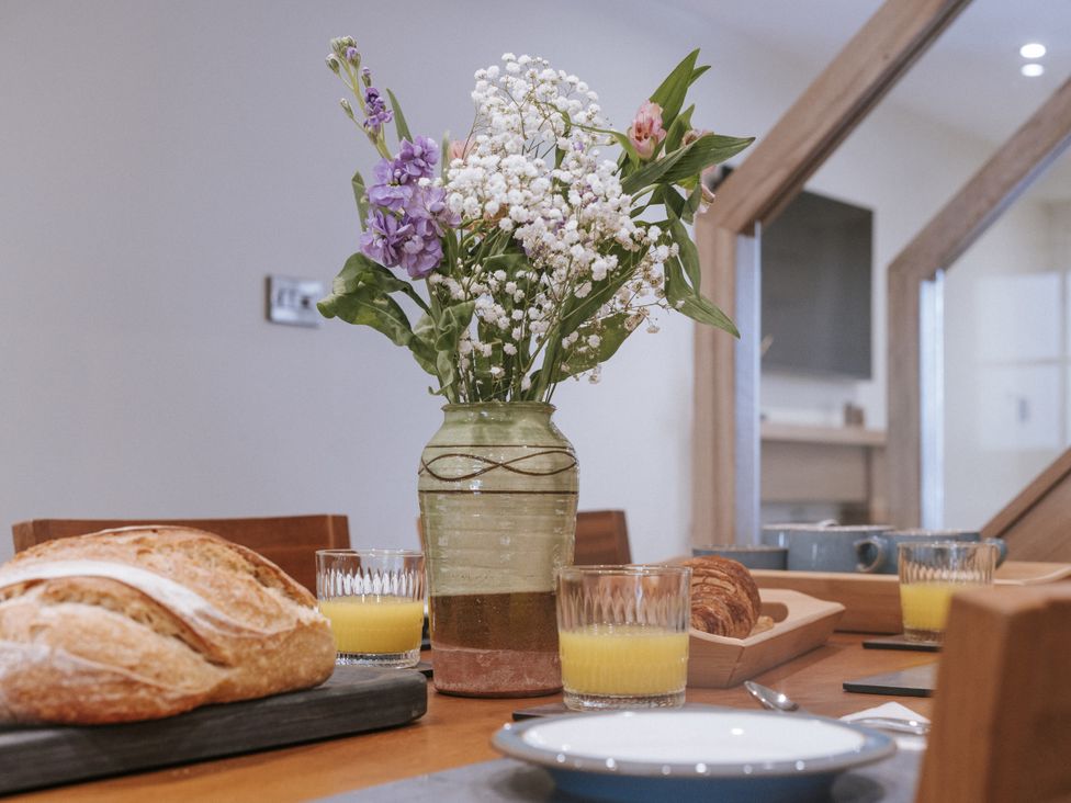 A dining room table with a flower vase juice and baked goods at Bluck's cottage in St. Agnes