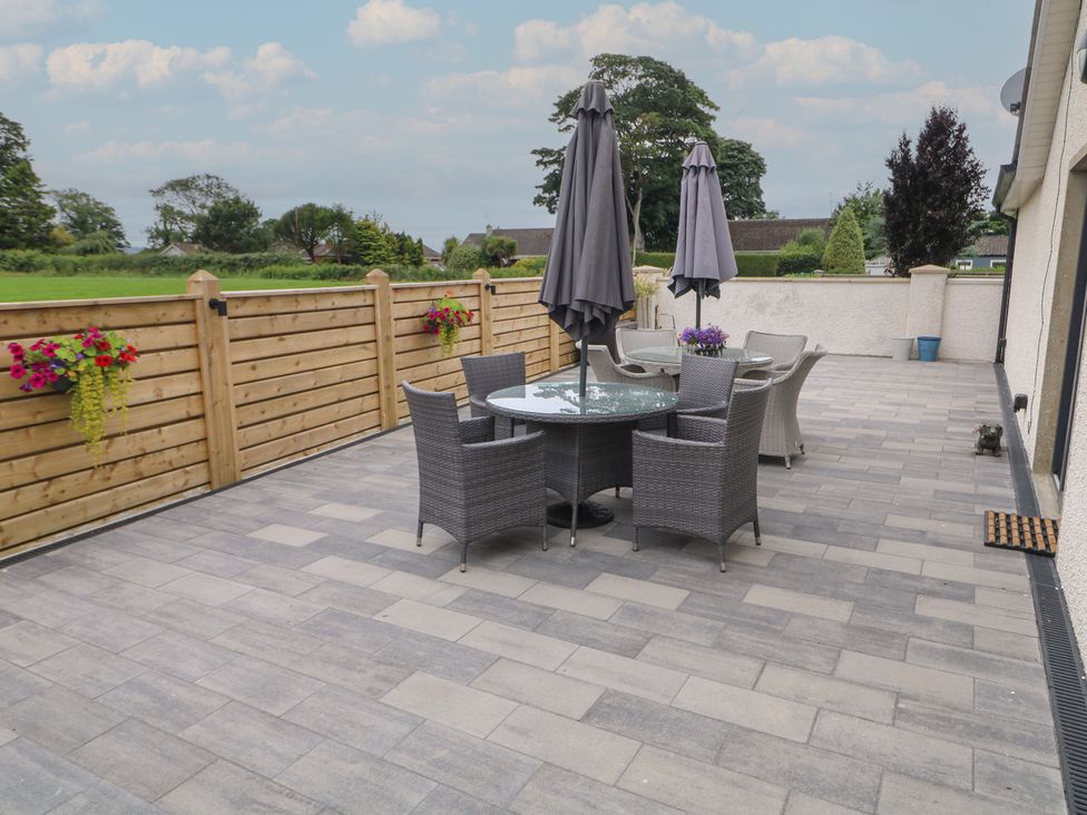 An outdoor patio with a table, chairs, and umbrellas at Clarmes House in Limavady