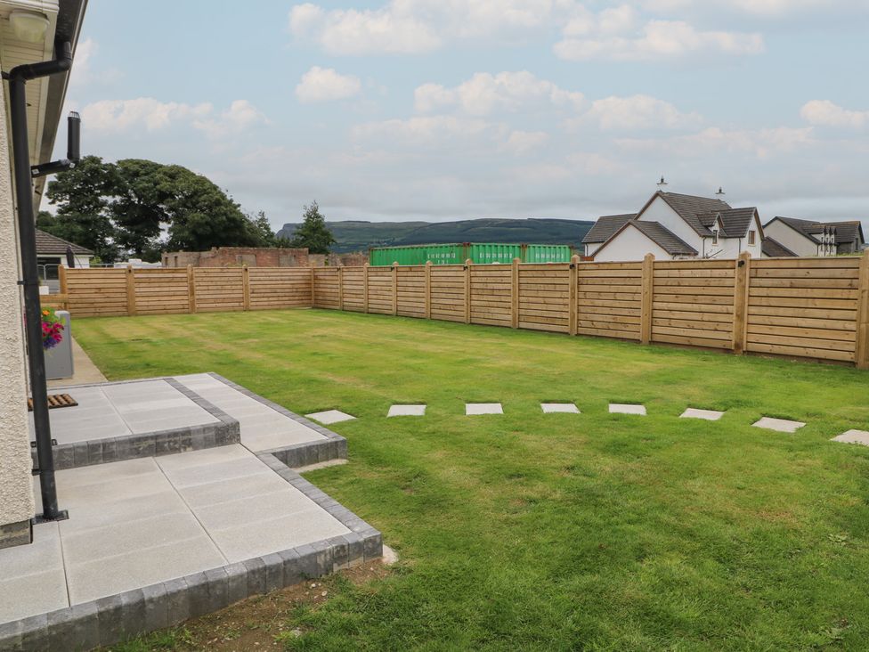 A garden with grass and a paved patio at Clarmes House in Limavady