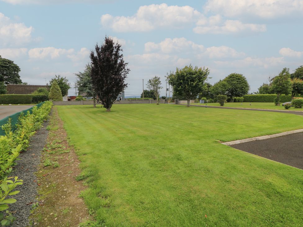 A garden with a large lawn and trees at Clarmes House Limavady