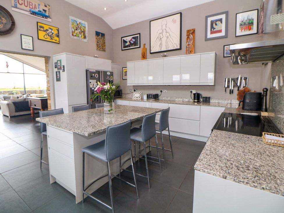 A kitchen featuring an island with chairs and a refrigerator at Highgate house