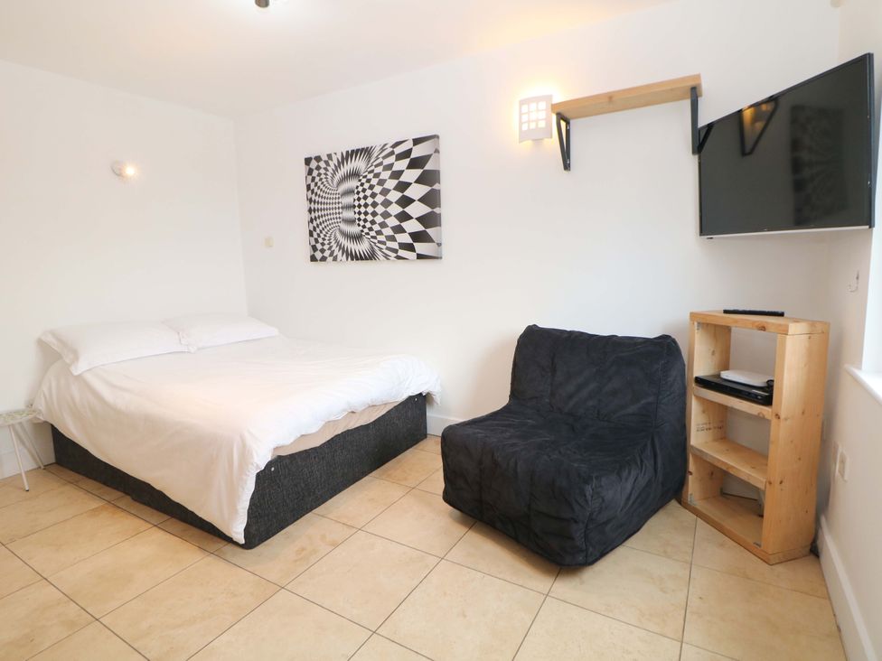 A bedroom with a bed, a chair, a TV and a shelf at Highgate house