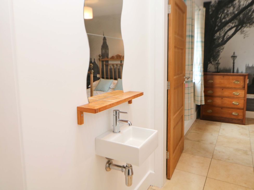 A bathroom with a sink and wooden shelf at Highgate house