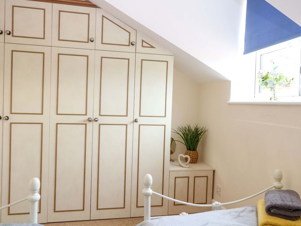 A bedroom with built-in wardrobe and a plant at Honeysuckle Cottage in Swaffham