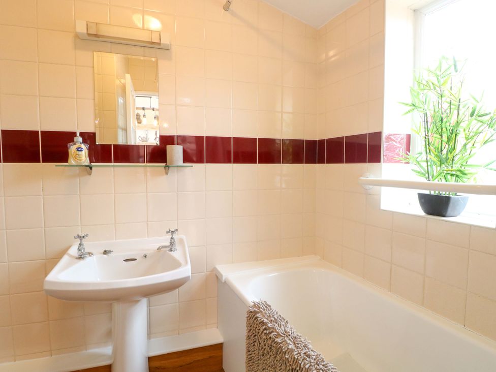 A bathroom with a sink and bathtub at Honeysuckle Cottage in Swaffham