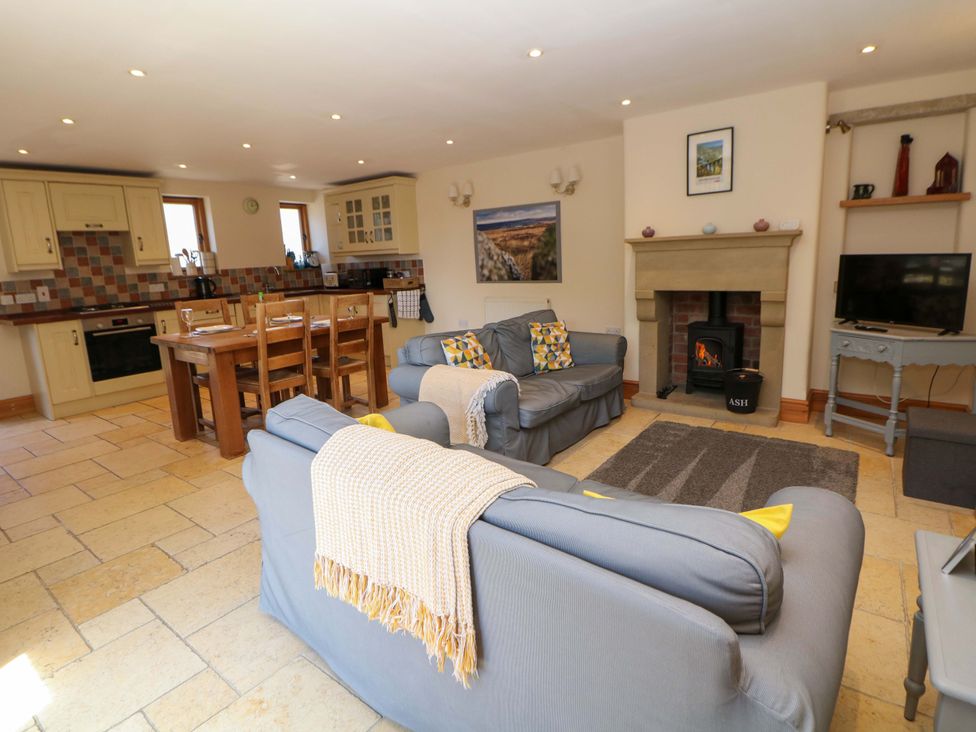 A living room with a sofa, dining table, and fireplace at Hollow Brook Cottage in Hope Valley