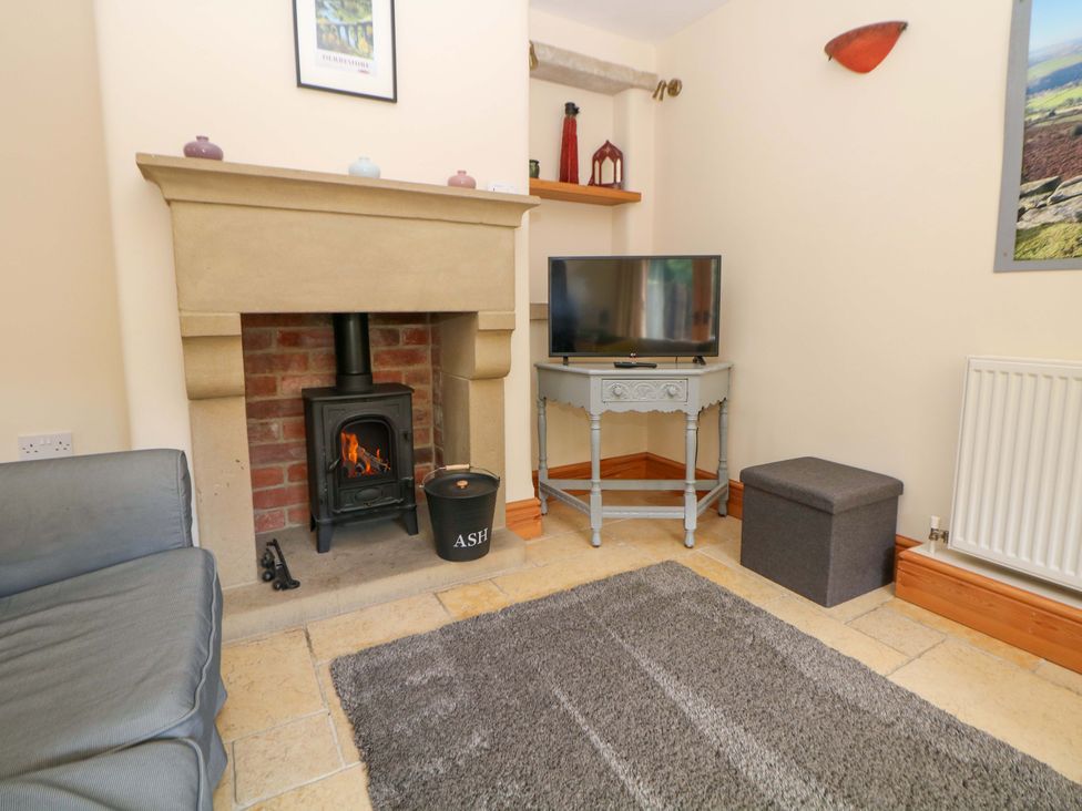 A living room with a fireplace and television at Hollow Brook Cottage, Hope Valley