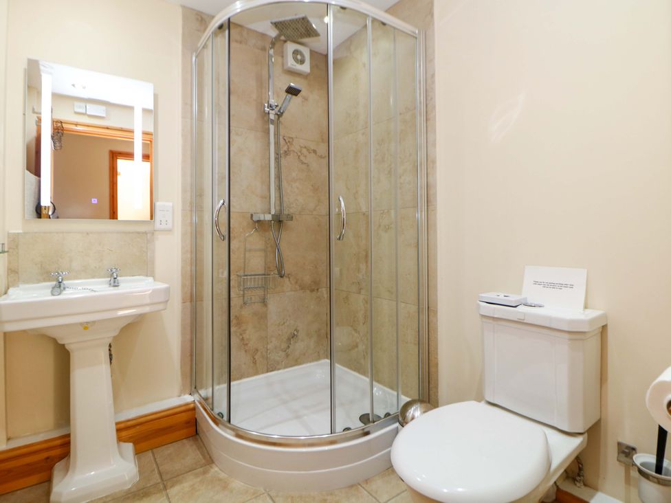 A bathroom with a shower, toilet, and sink at Hollow Brook Cottage in Hope Valley