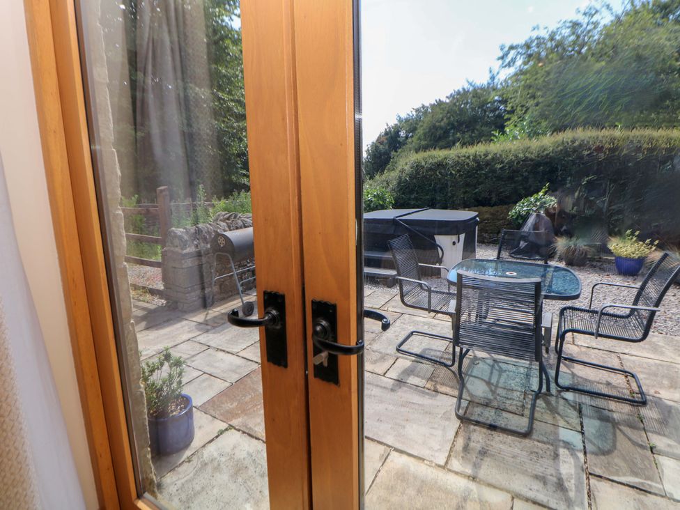 A garden with a table and chairs and a hot tub at Hollow Brook Cottage in Hope Valley