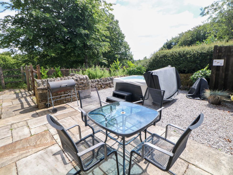 An outdoor area with a table and chairs alongside a hot tub at Hollow Brook Cottage in Hope Valley