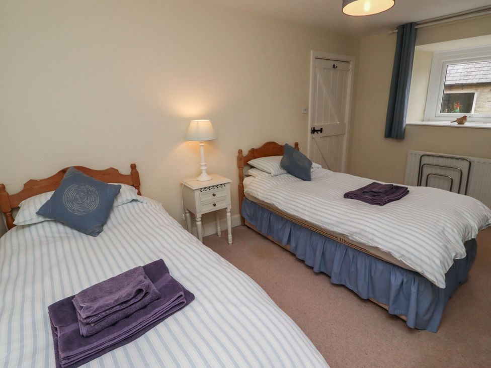 A bedroom with two beds and a bedside table at Honeymug in Branton near Powburn