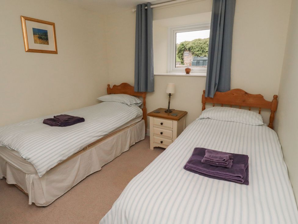 A bedroom with two single beds and a bedside table at Honeymug in Branton near Powburn
