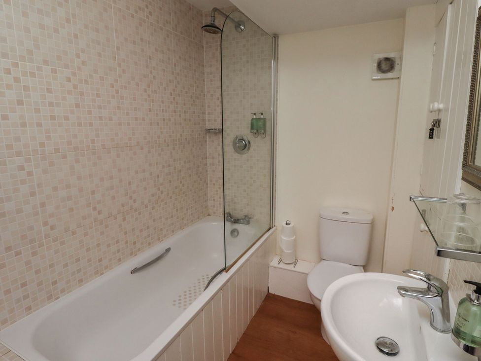 A bathroom with a bathtub, shower, toilet, and sink at Honeymug in Branton near Powburn