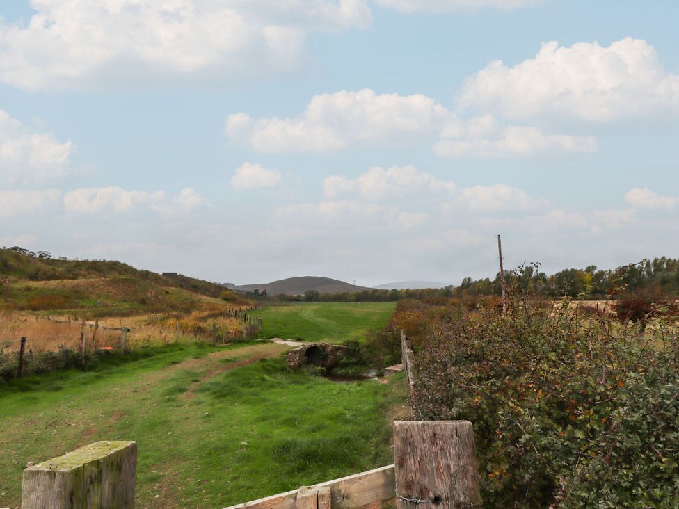 A grassy path with a fence and hills at Honeymug in Branton near Powburn