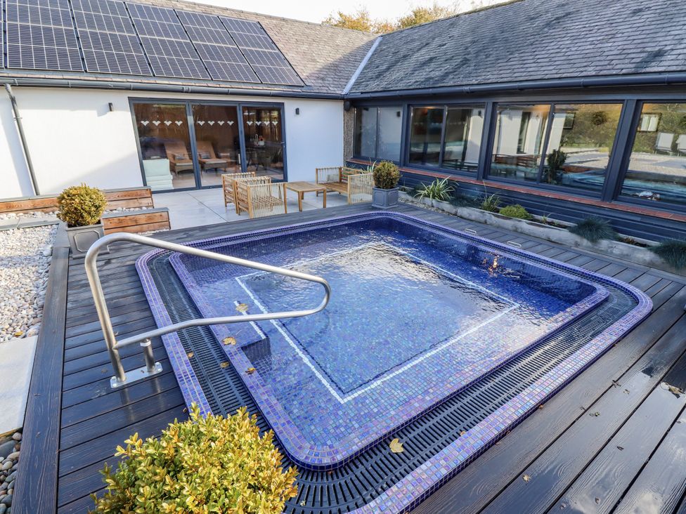 A hot tub with seating area and solar panels at Honeymug in Branton near Powburn