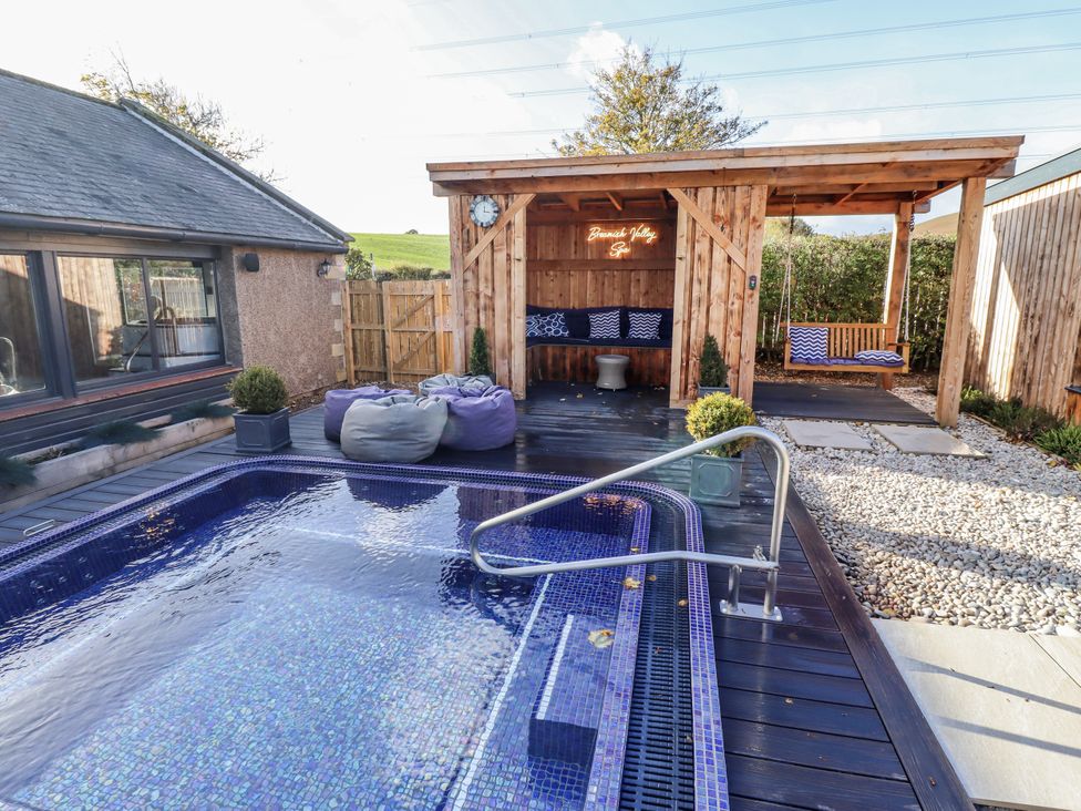An outdoor area with a swimming pool and wooden structure at Honeymug in Branton near Powburn