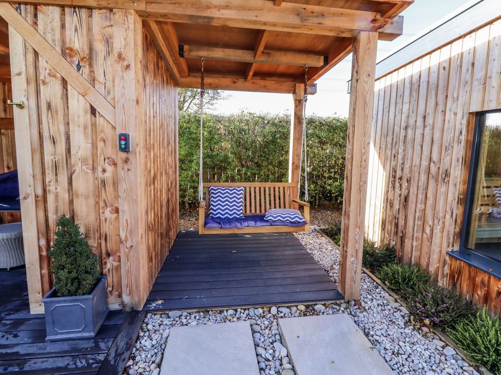 An outdoor area with a swing seat and wooden structure at Honeymug in Branton near Powburn