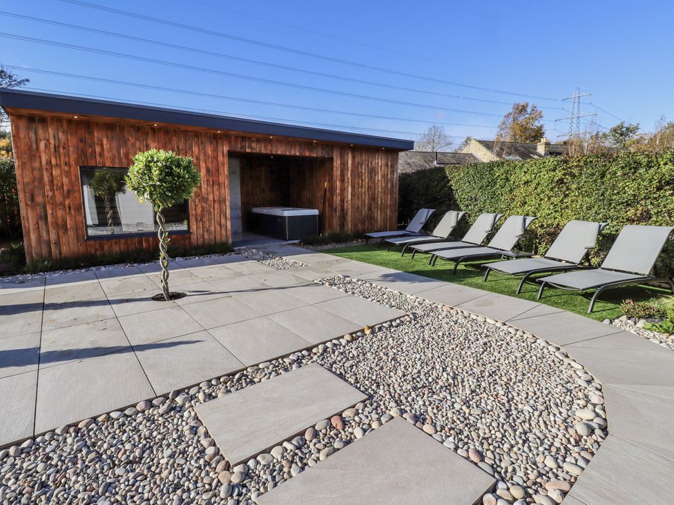 A garden with a wooden building and lounge chairs at Honeymug in Branton near Powburn